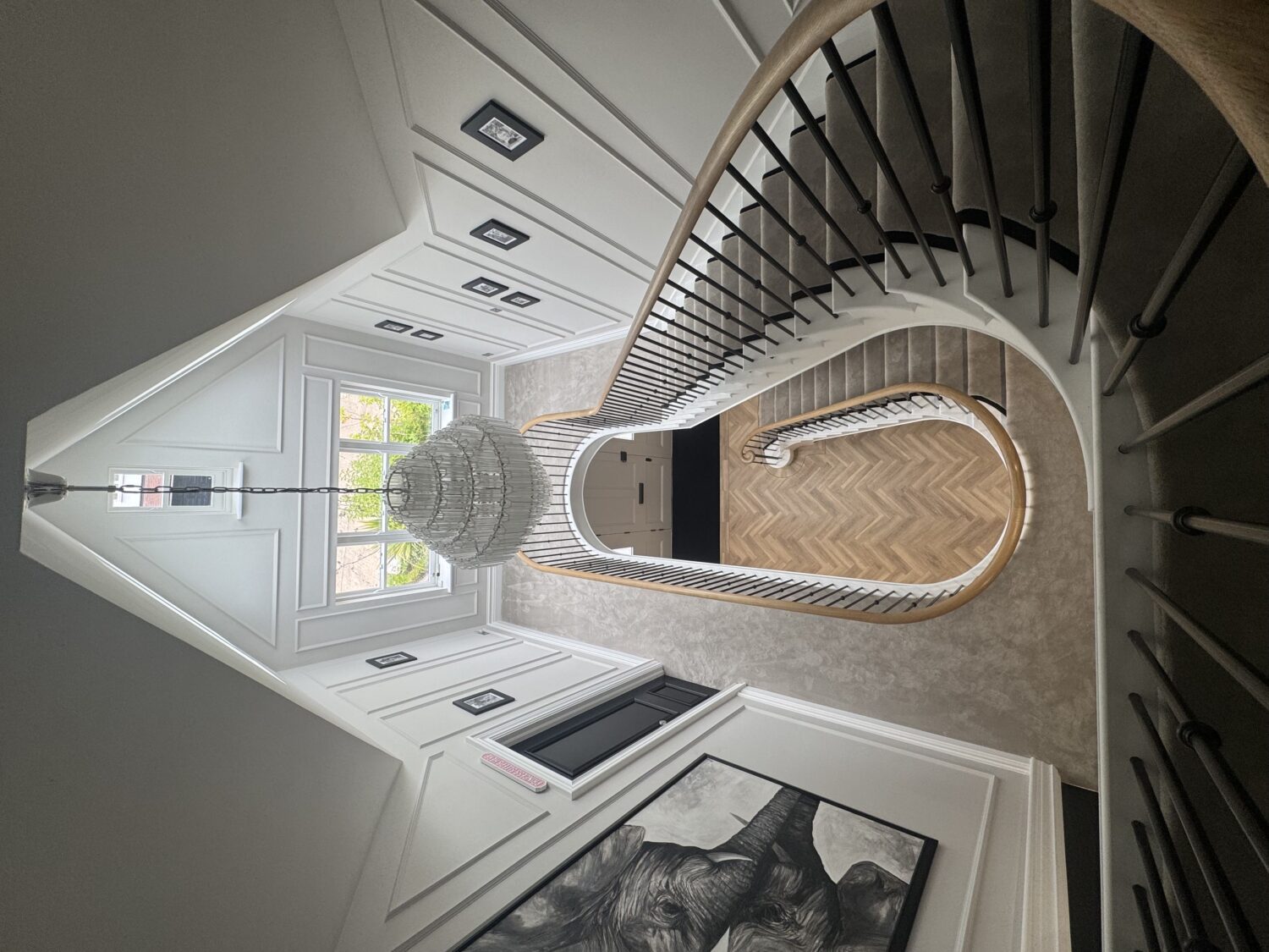 Curved staircase viewed from the top landing, showing the continuous oak handrail following the full curve of the stairwell